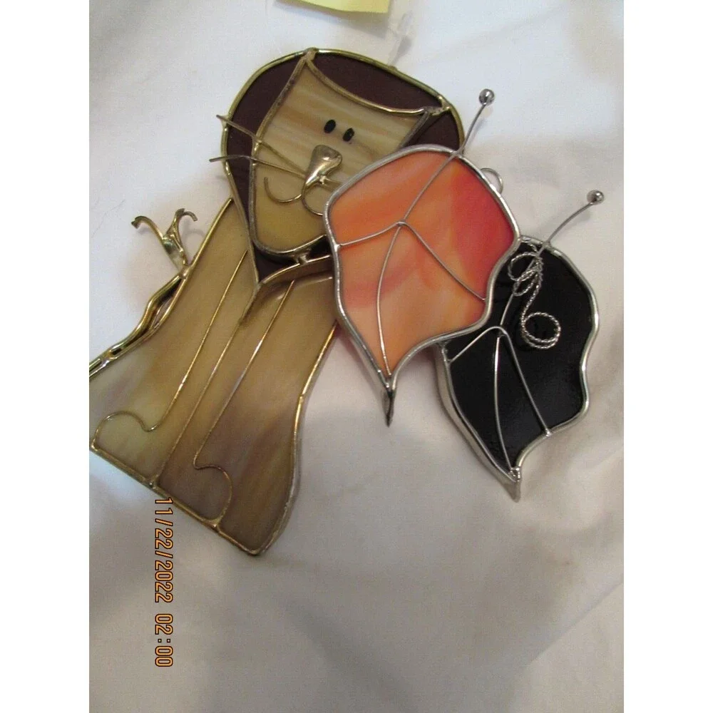 Stained glass leaves and lion handmade ornaments hang in window